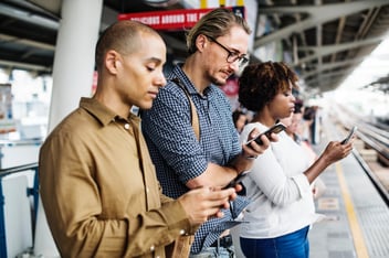 people looking at phones waiting for train